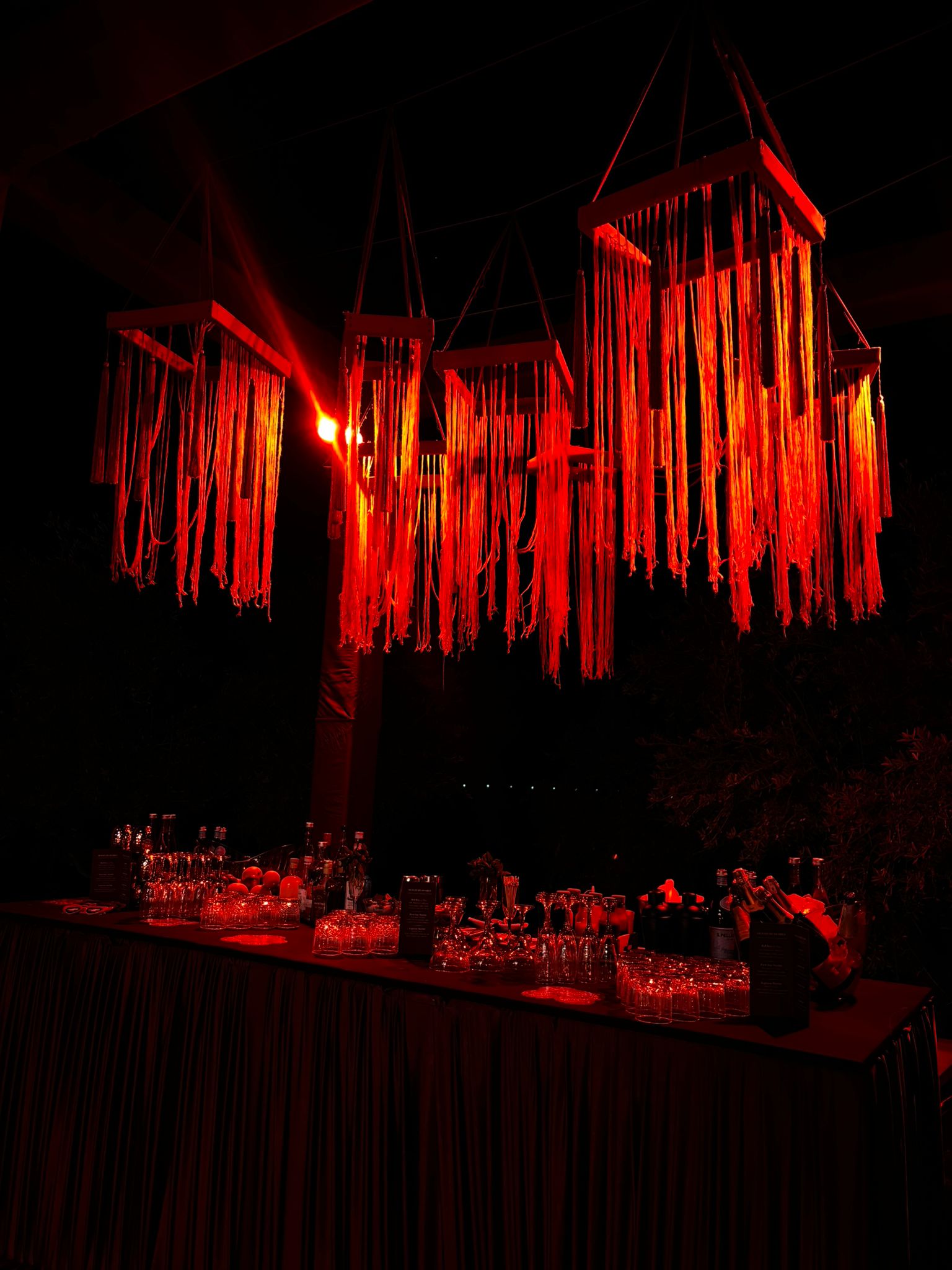Bar monumental sous installation rouge — Scénographie de soirée